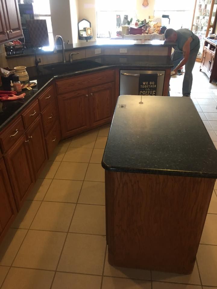 A kitchen with a black counter top and wooden cabinets