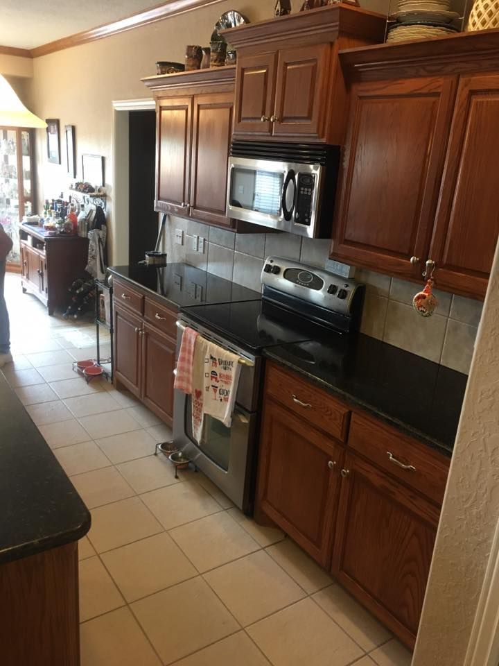 A kitchen with wooden cabinets , a stove , a microwave , and a sink.