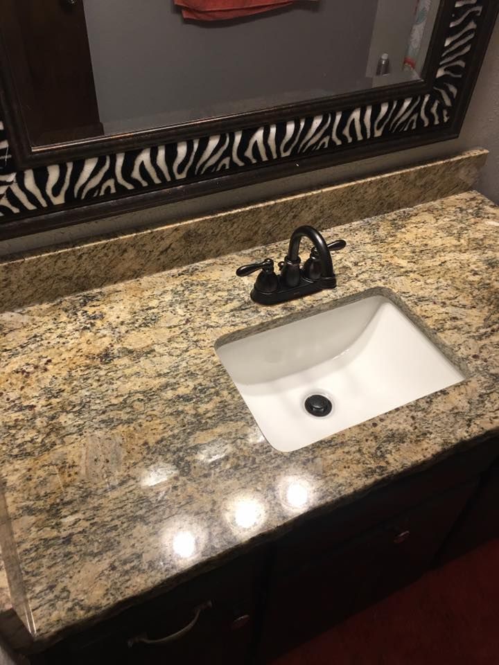 A bathroom sink with a black faucet and a mirror.