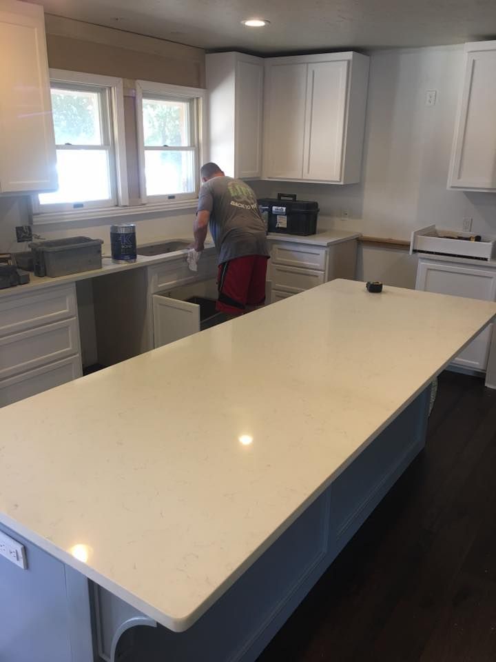 A man is working in a kitchen with a large white counter top.