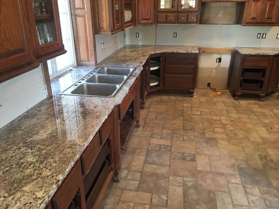 A kitchen with granite counter tops and wooden cabinets.