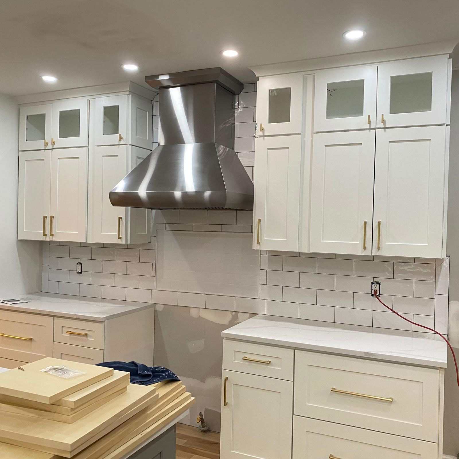 Modern white kitchen with stainless steel range hood and cabinets under construction