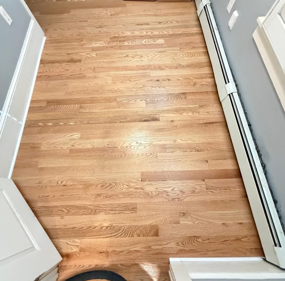 Hallway with light wood floor and gray walls, viewed from an open doorway.