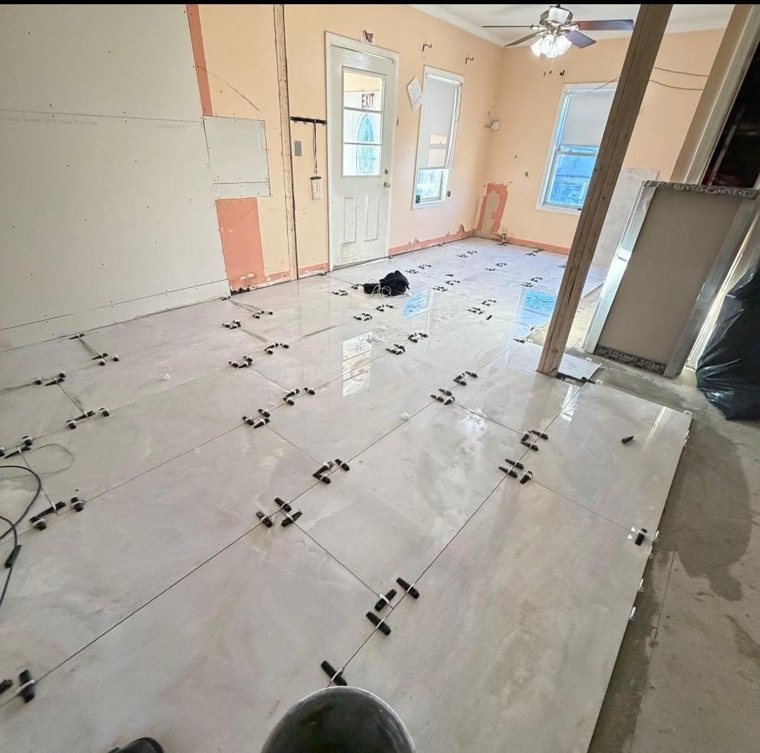 Empty room under renovation with white tile flooring, peach walls, and windows letting in daylight