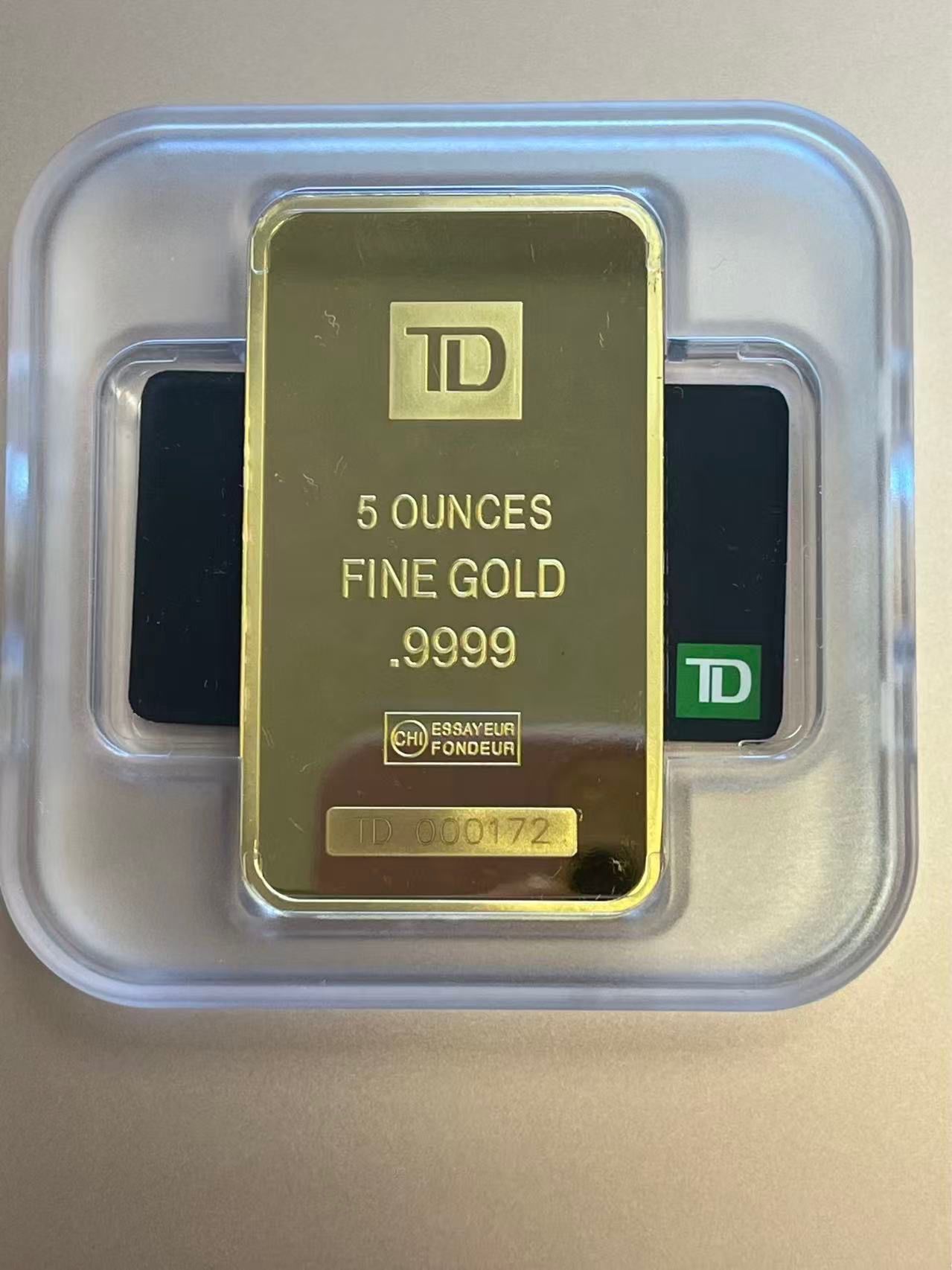 A 5-ounce, .9999 fine gold TD bank bar in a protective clear plastic case.