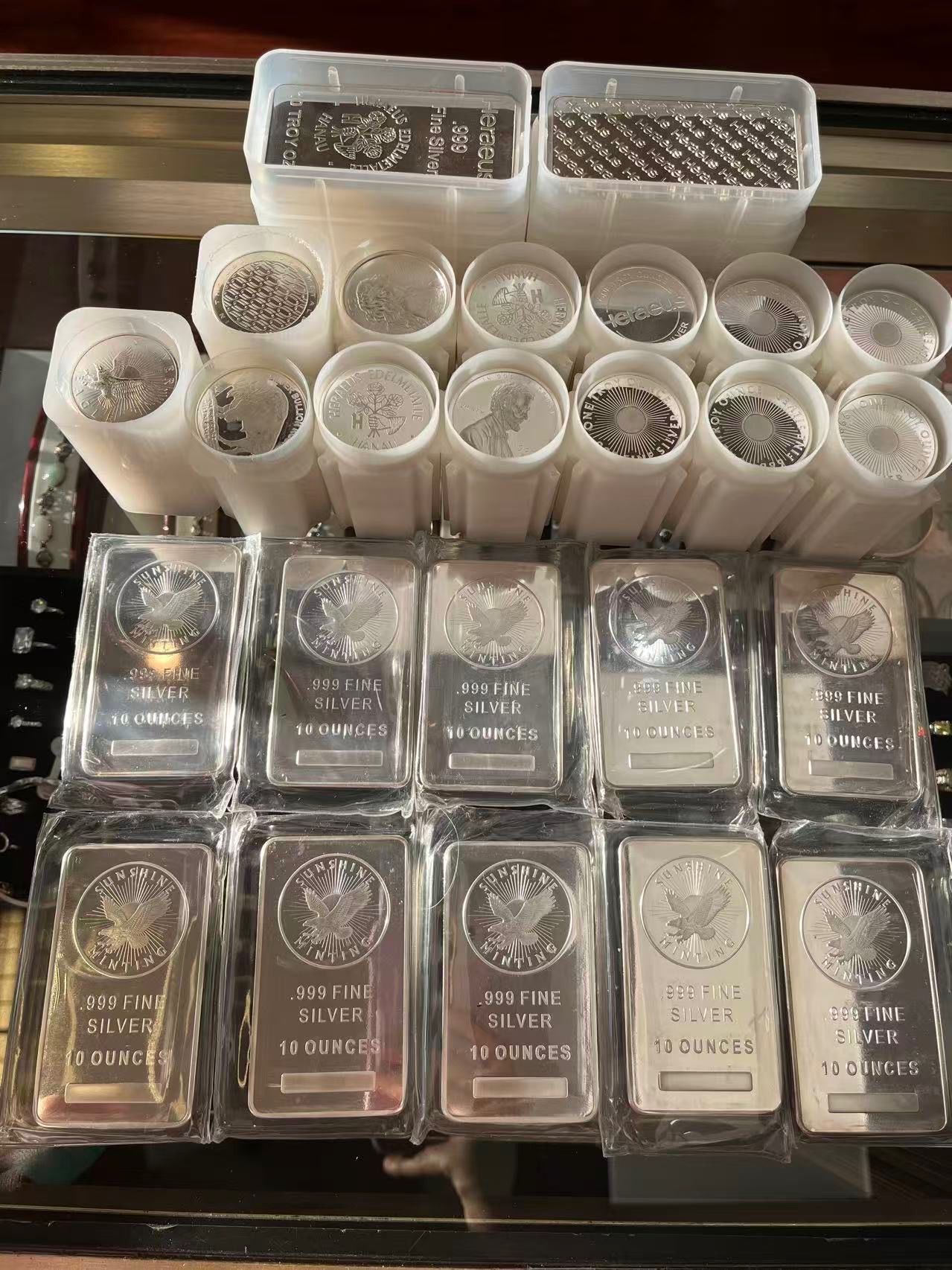 A large collection of silver bars and tubes of silver coins stacked on a surface.