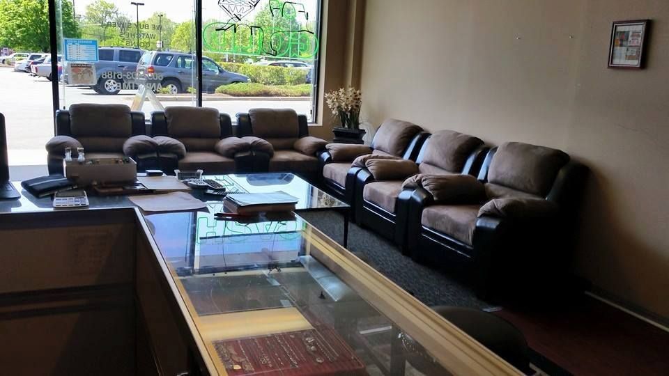 Interior of a jewelry store waiting area with brown couches, a glass counter, and a window overlooking a parking lot.