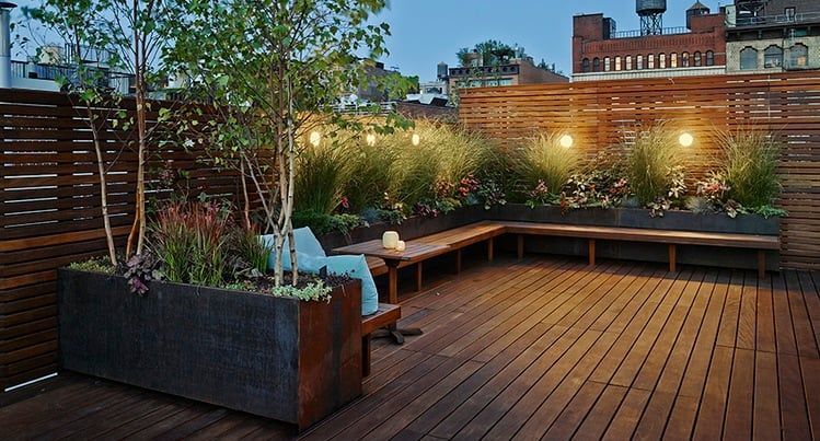 A wooden deck with a bench and planters on it.