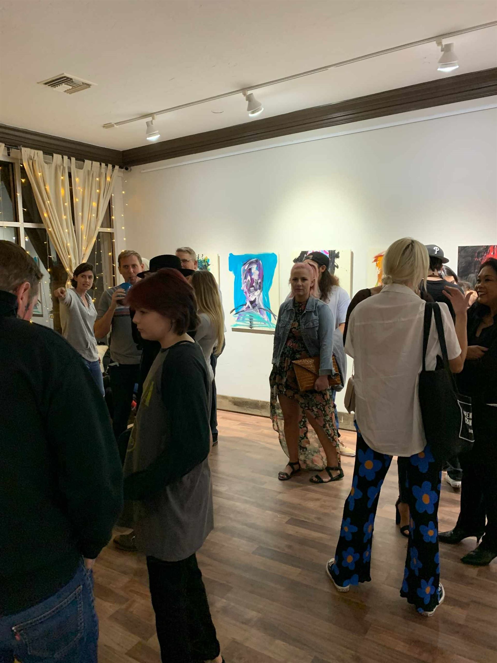 A group of people are standing in a room looking at paintings.