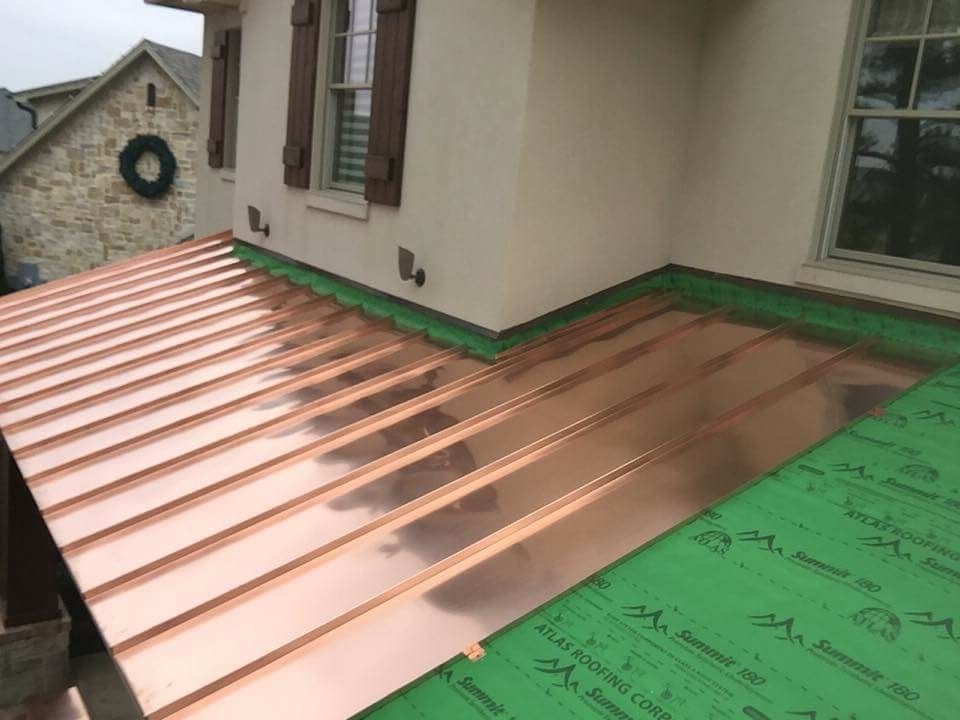 A copper roof is being installed on the side of the house