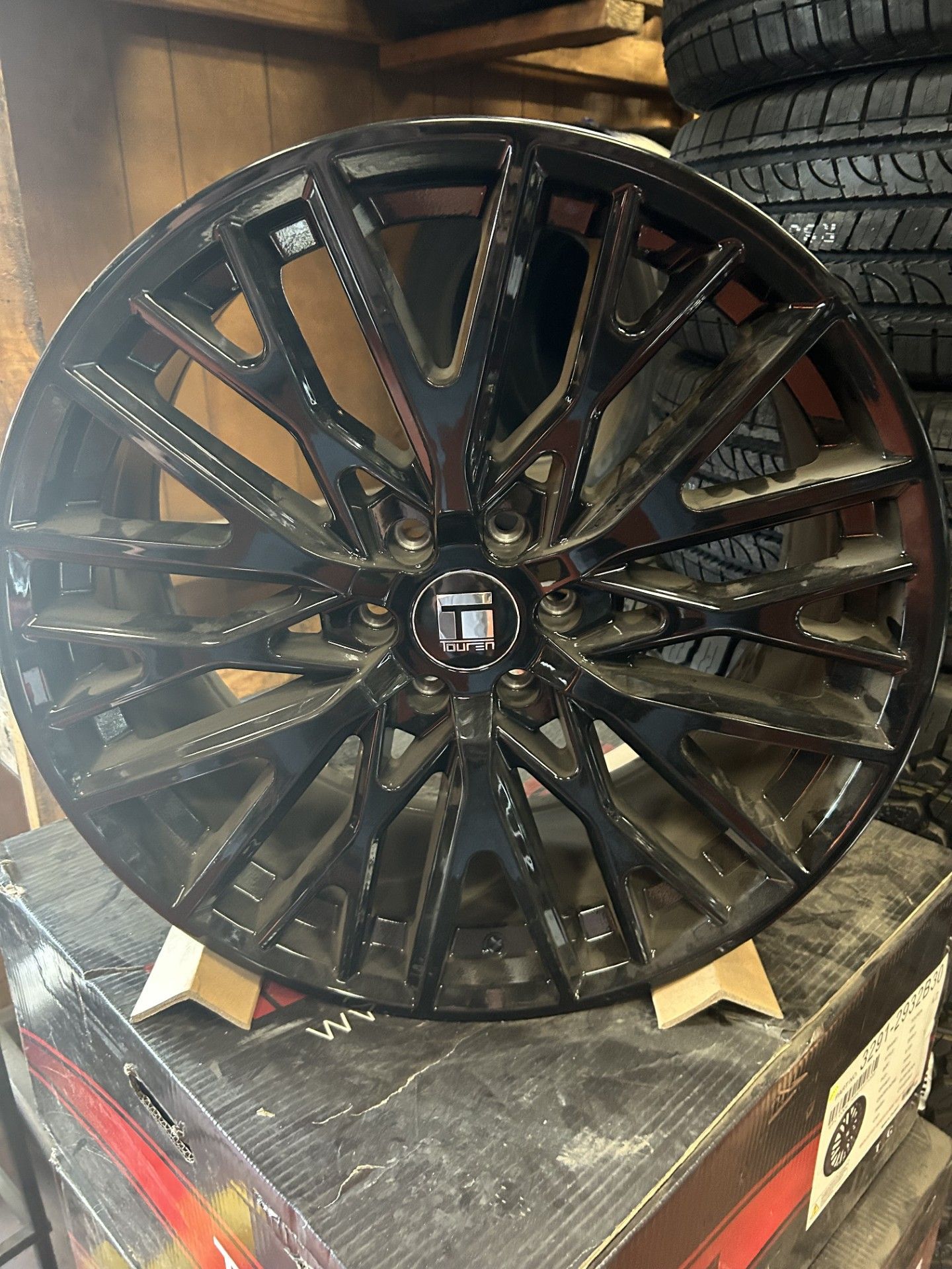 A black wheel is sitting on top of a stack of tires.