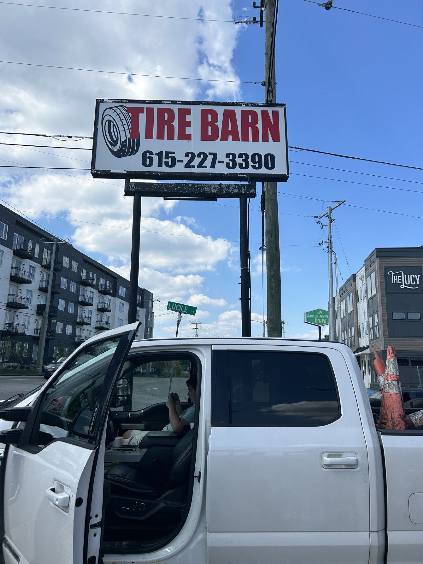 A white truck is parked in front of a tire barn sign.