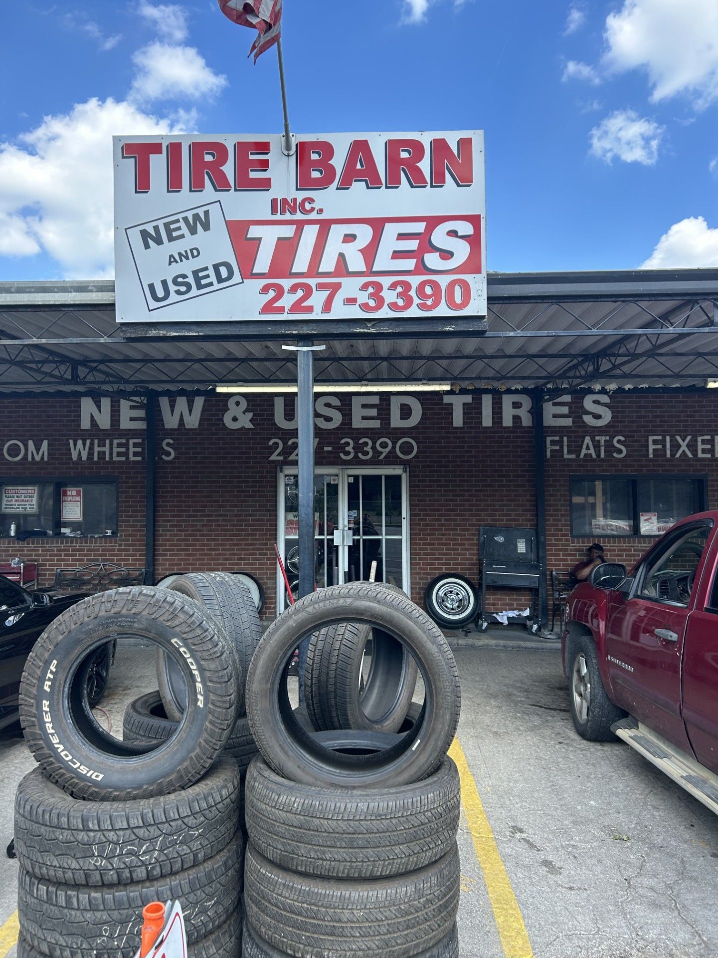 A stack of tires is in front of a tire barn store.
