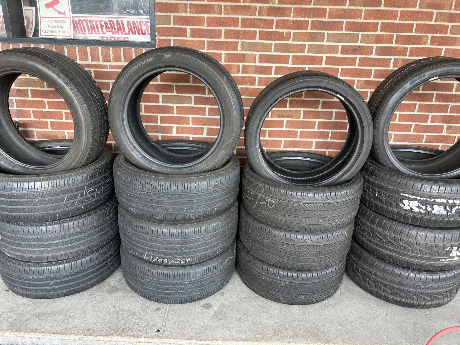 A bunch of tires are stacked on top of each other in front of a brick wall.