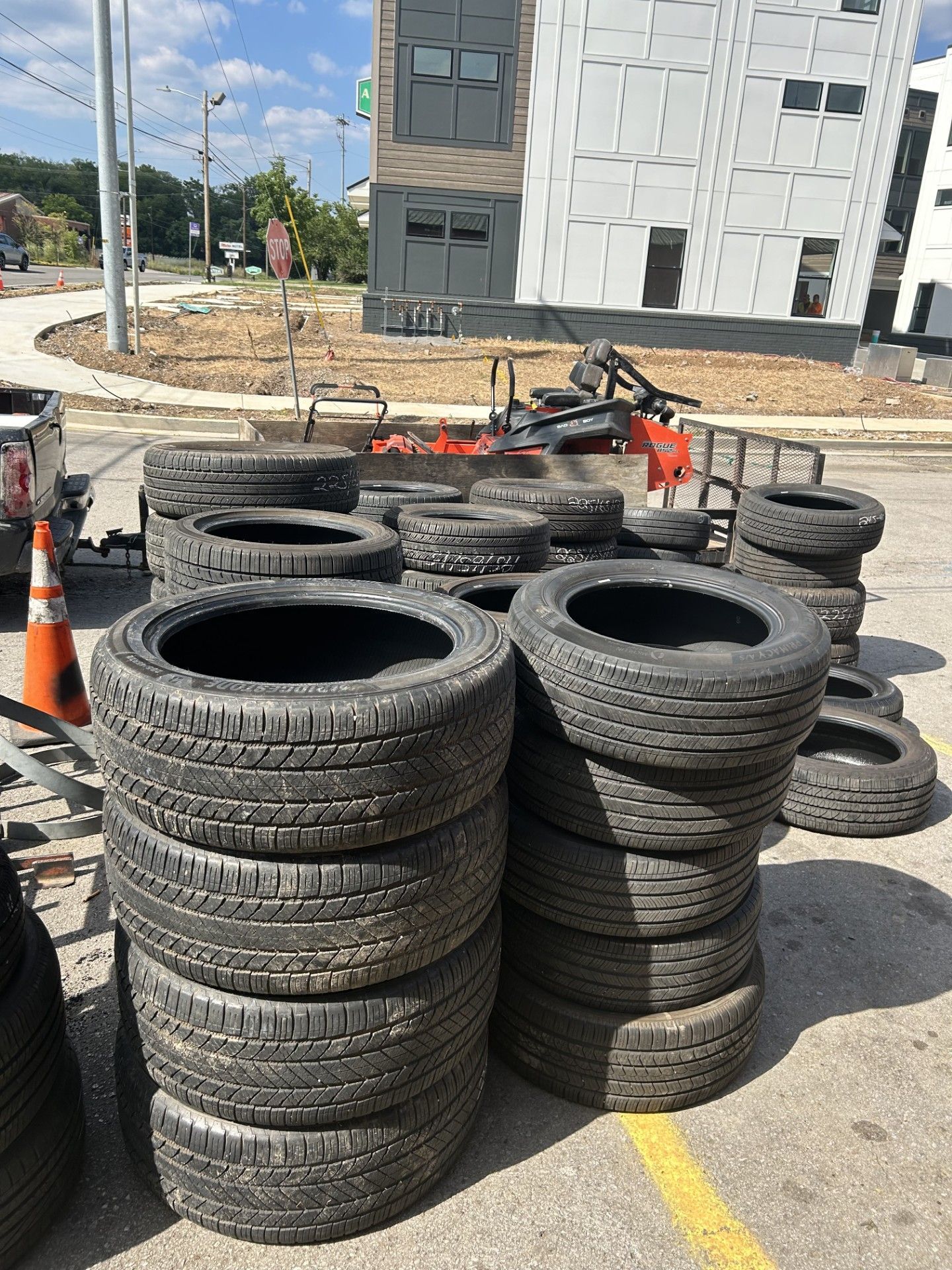 A bunch of tires are stacked on top of each other in a parking lot.