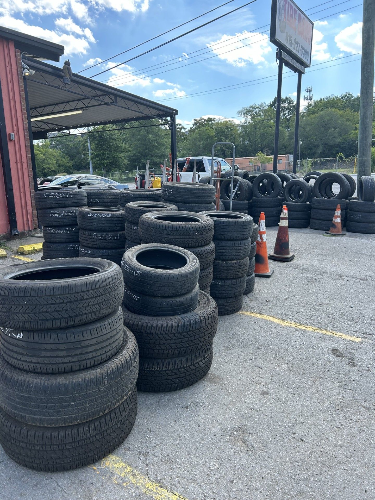 A lot of tires are stacked on top of each other in a parking lot.