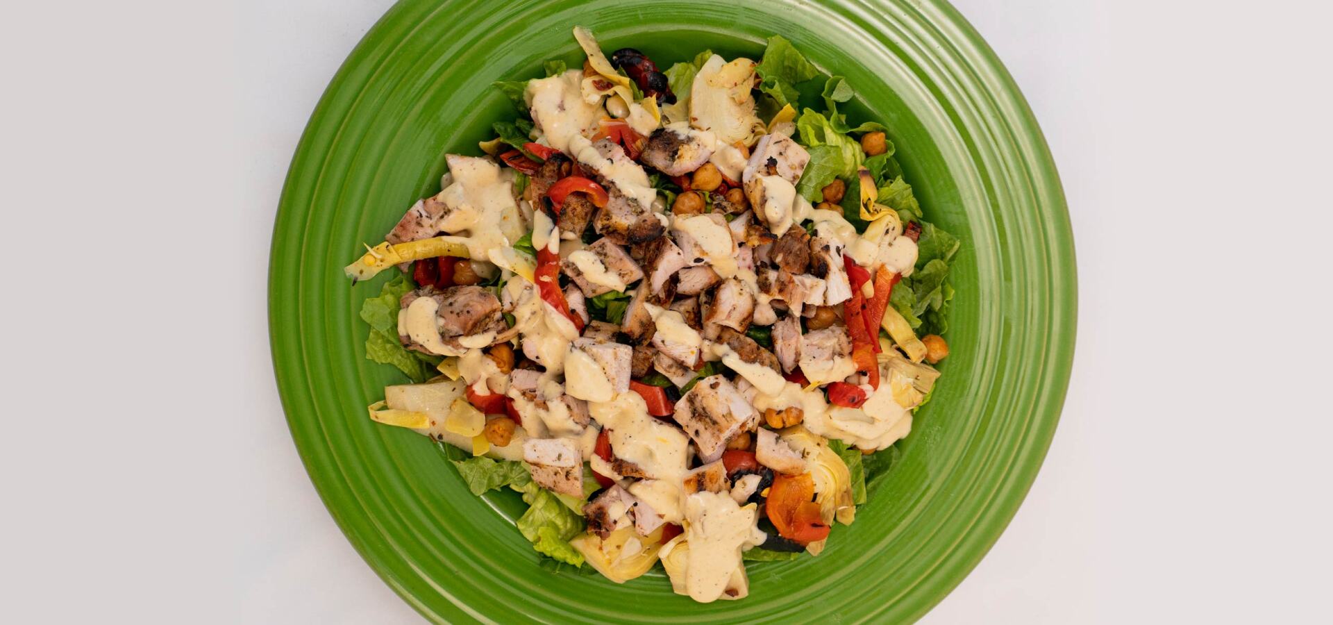 A green plate topped with a salad on a table