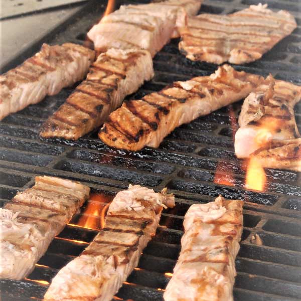 Several pieces of meat are cooking on a grill