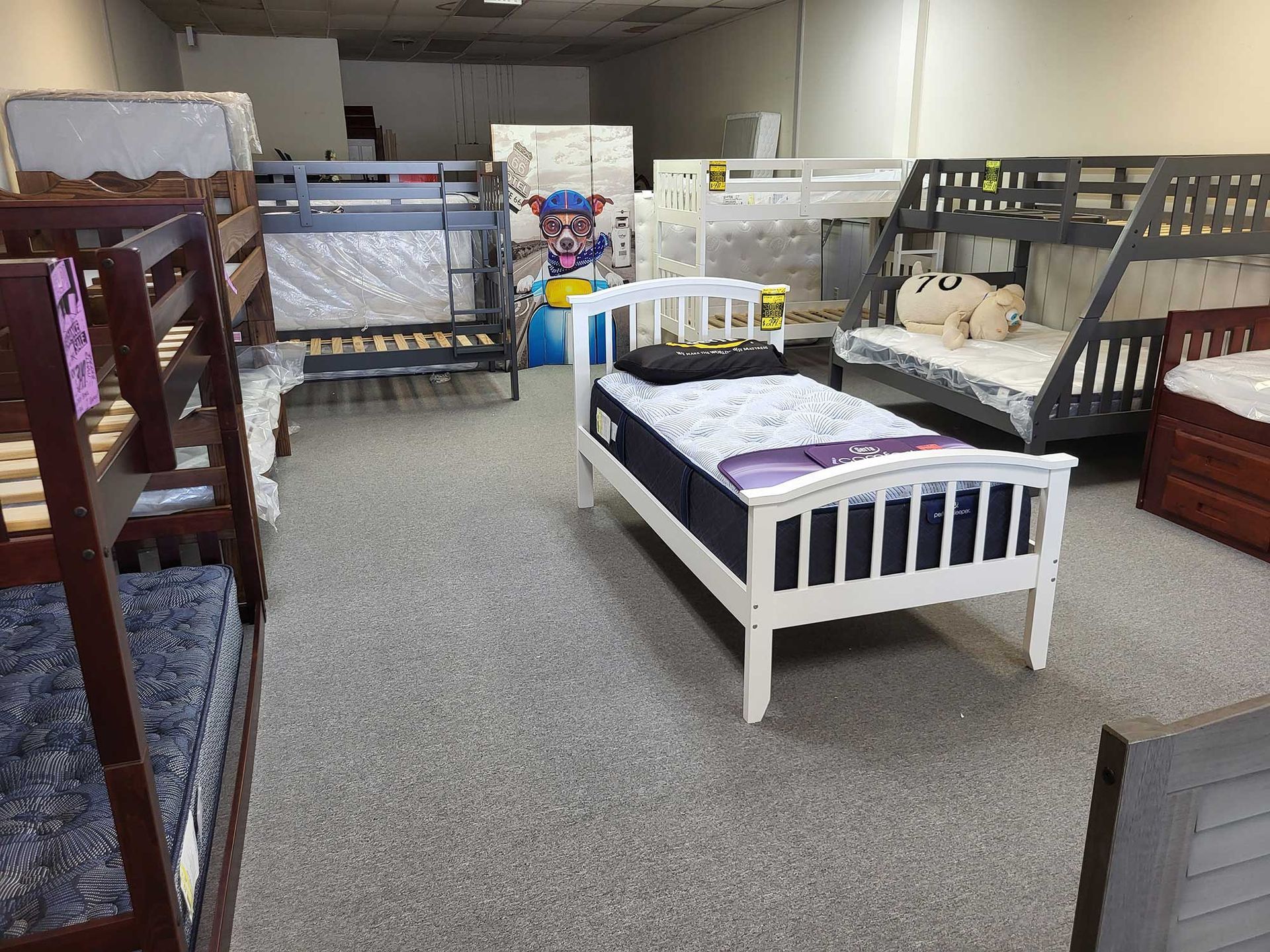 Interior of a furniture store displays multiple bunk beds and a twin bed on a carpeted floor.
