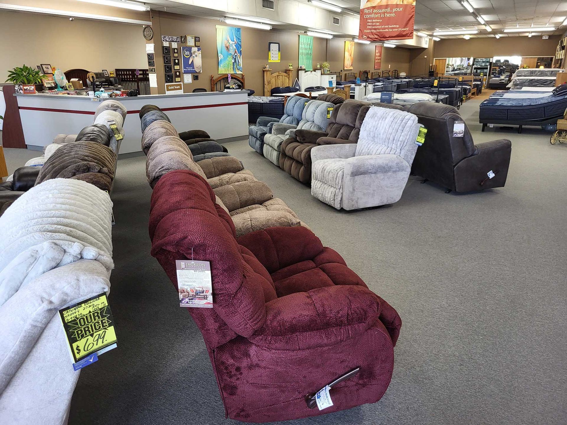 A furniture store interior displays rows of recliners in various colors and fabrics.