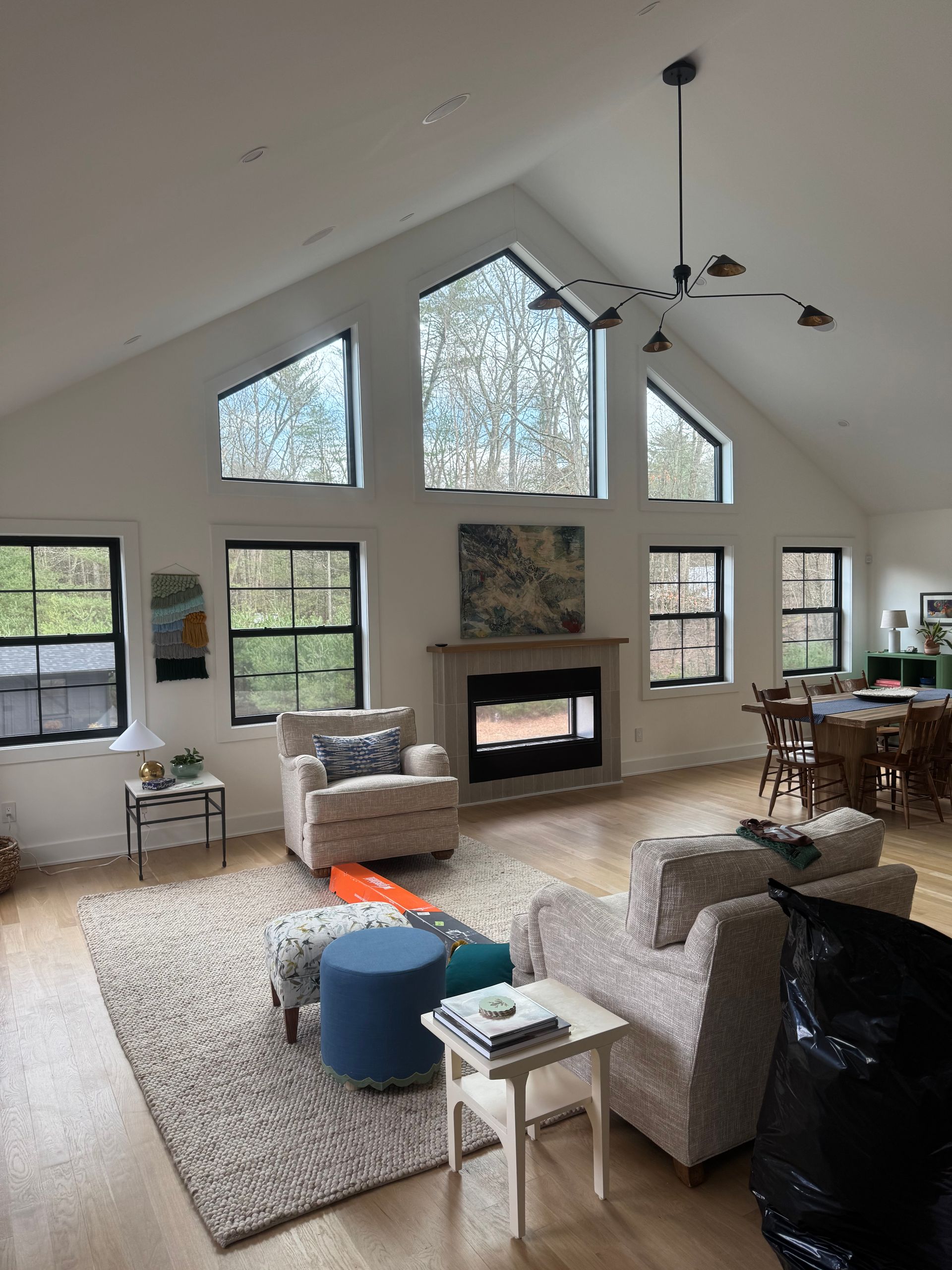 A bright, modern living room with high vaulted ceilings, large windows, a fireplace, and comfortable seating.