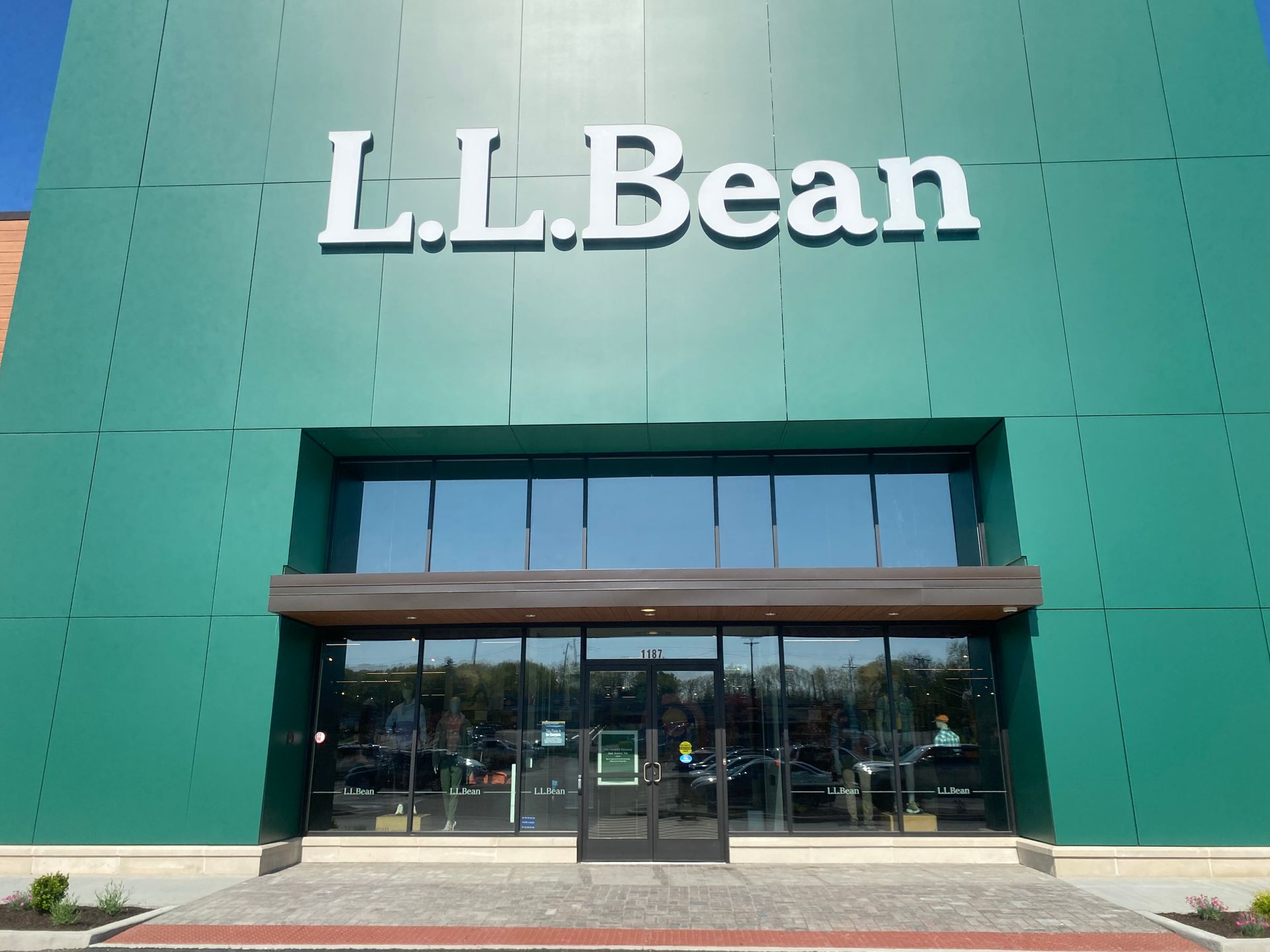 The storefront of an L.L. Bean retail location featuring a large, green panel exterior and glass entry doors.