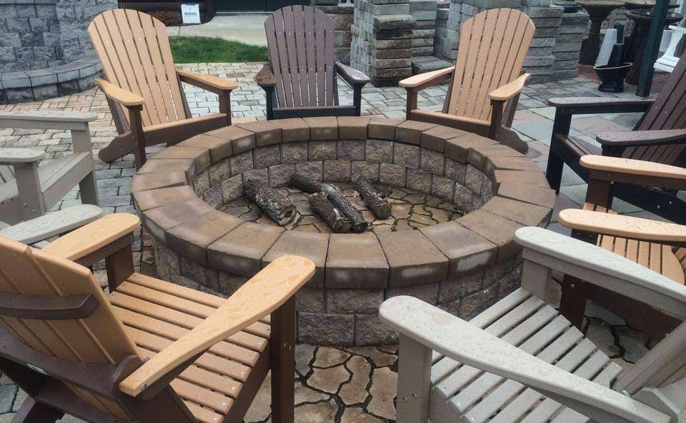 A fire pit surrounded by wooden chairs on a patio.