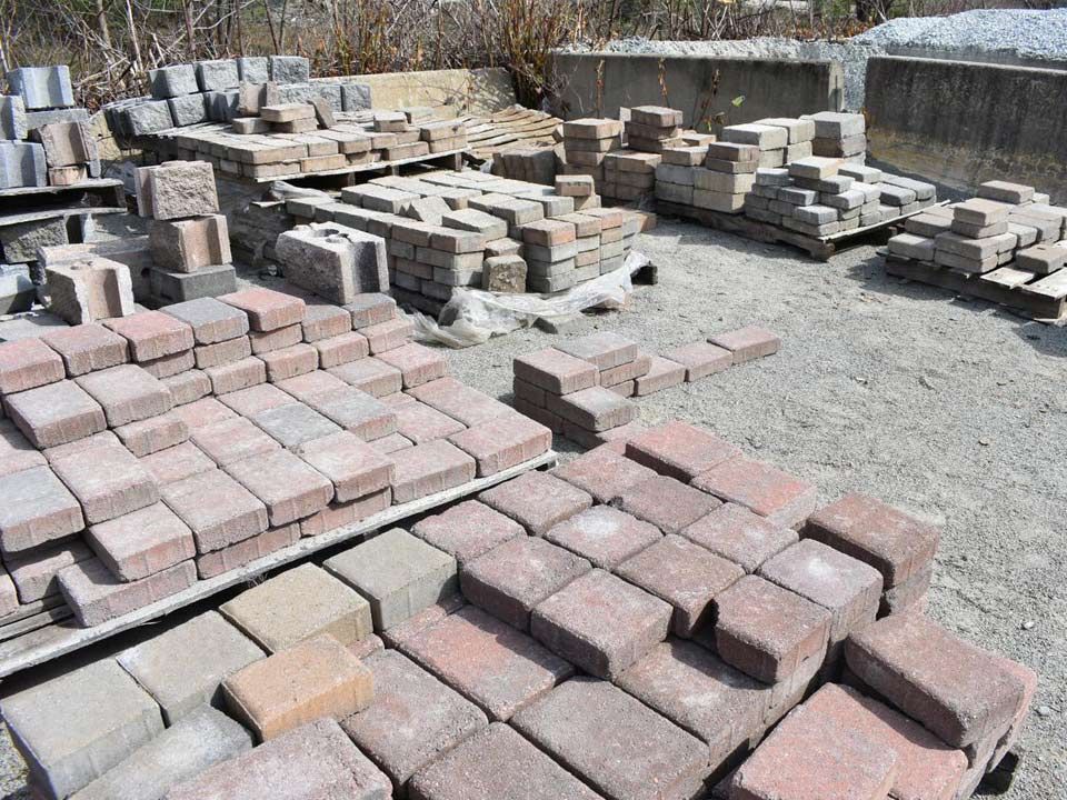 A bunch of bricks are stacked on top of each other in a yard.