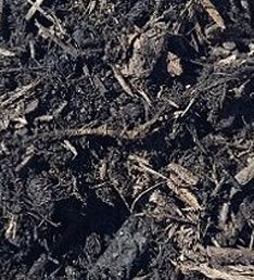A pile of black mulch is sitting on the ground.