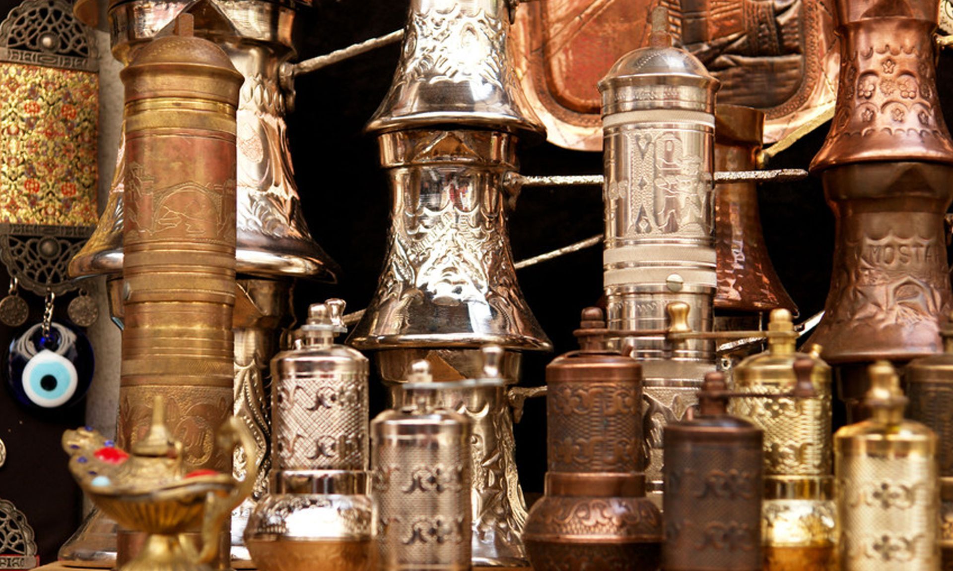 Assorted brass and copper lanterns and decorative vessels stacked closely together in a market display