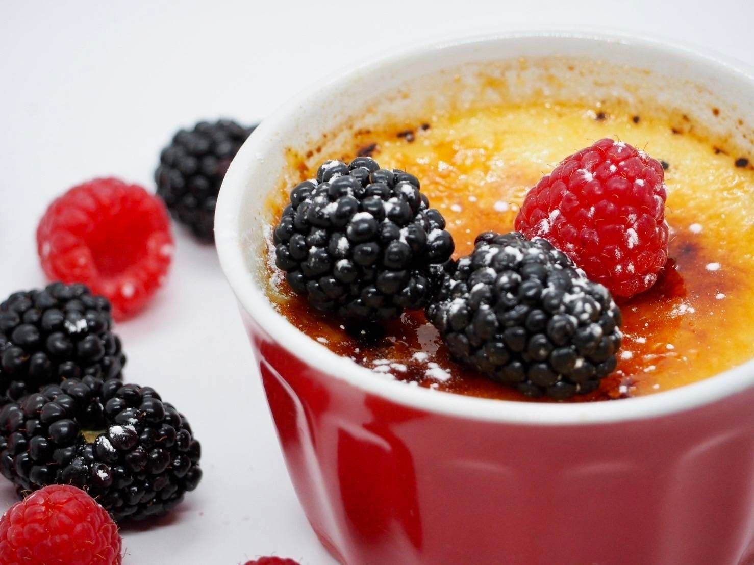 A bowl of dessert with blackberries and raspberries on top
