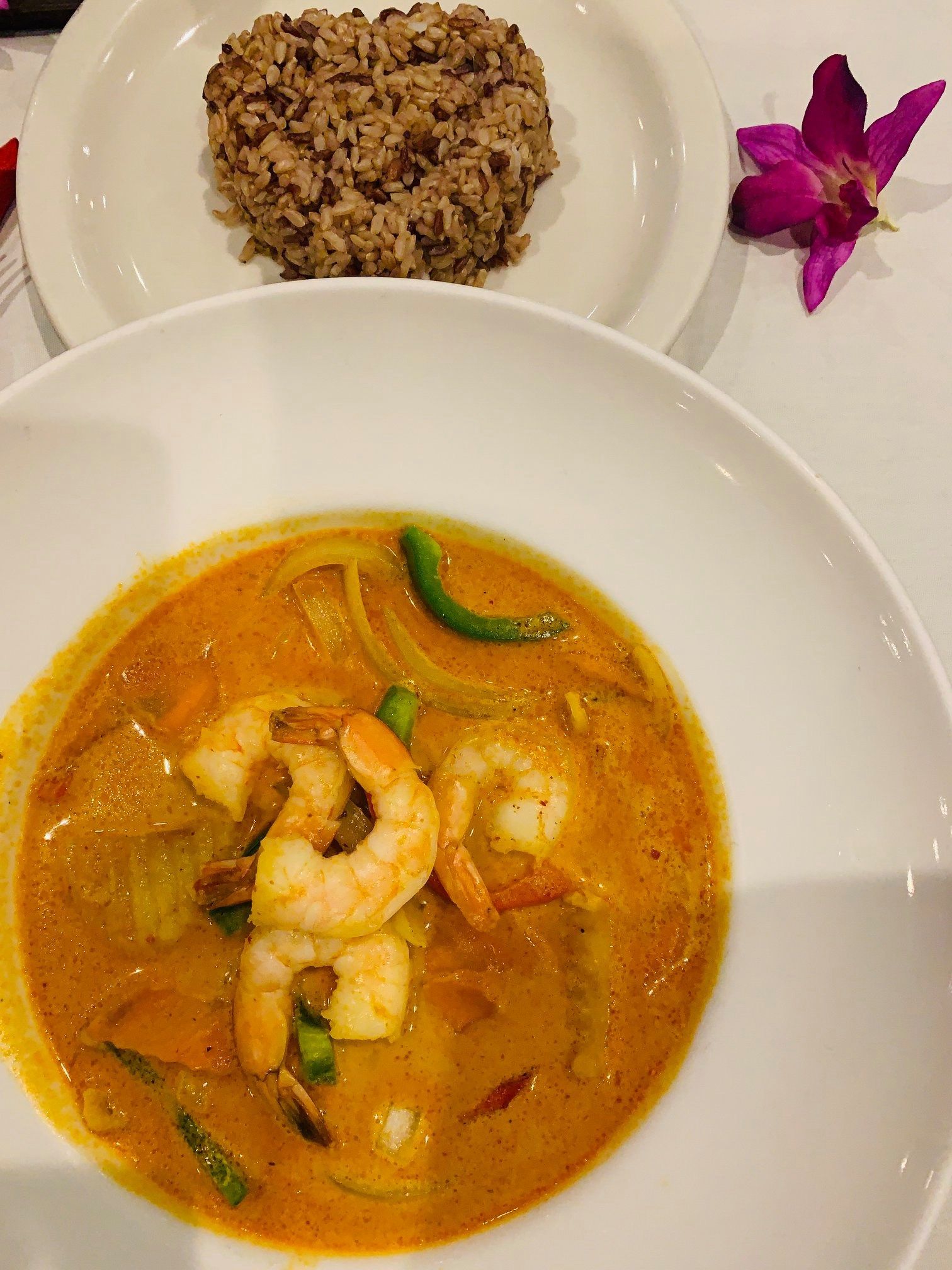 A bowl of shrimp curry next to a plate of rice.