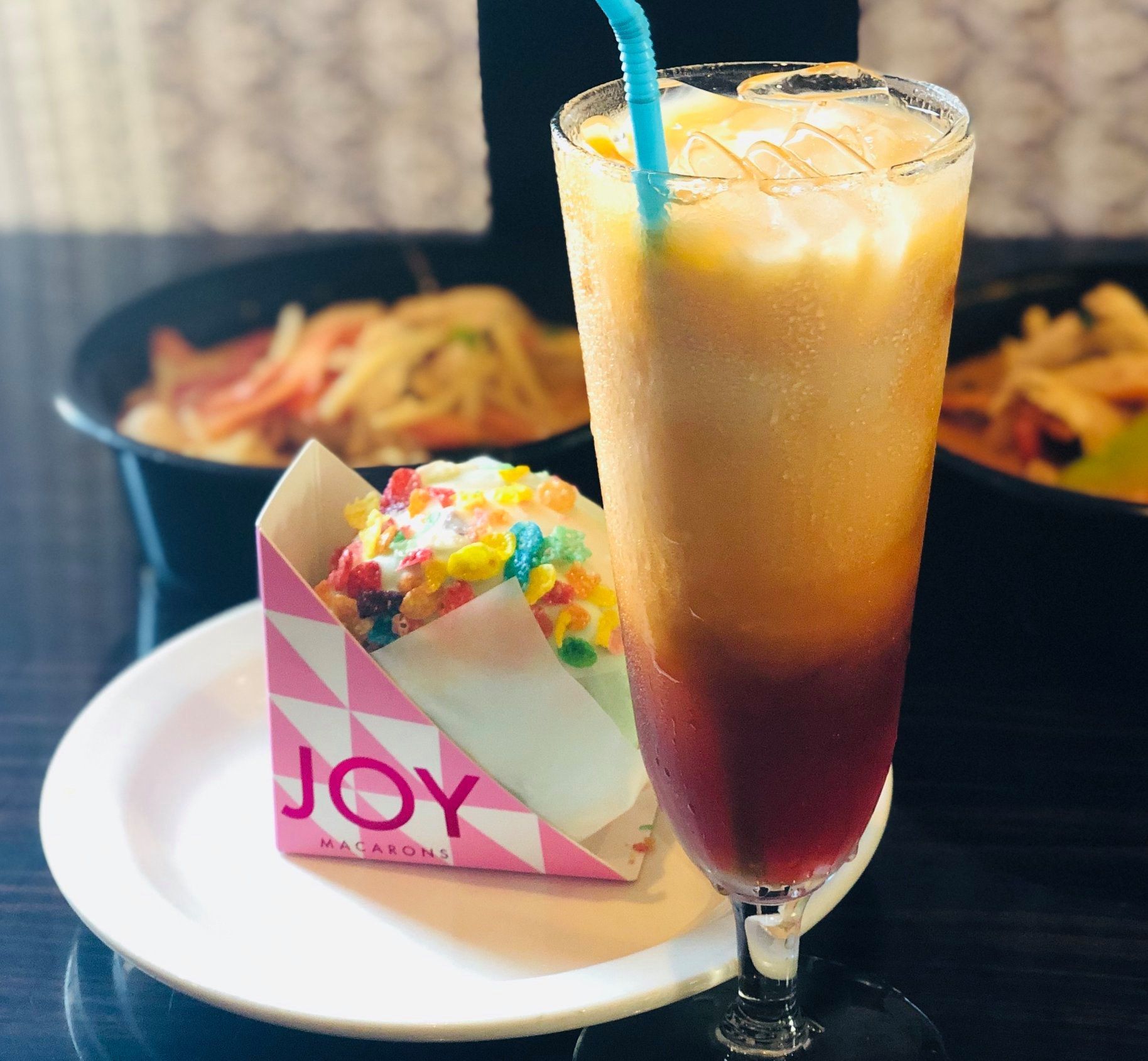 A cup of joy sits on a plate next to a drink