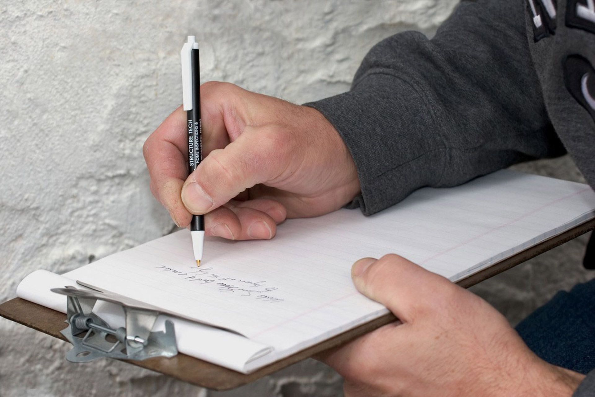 A person is writing on a clipboard with a pen.