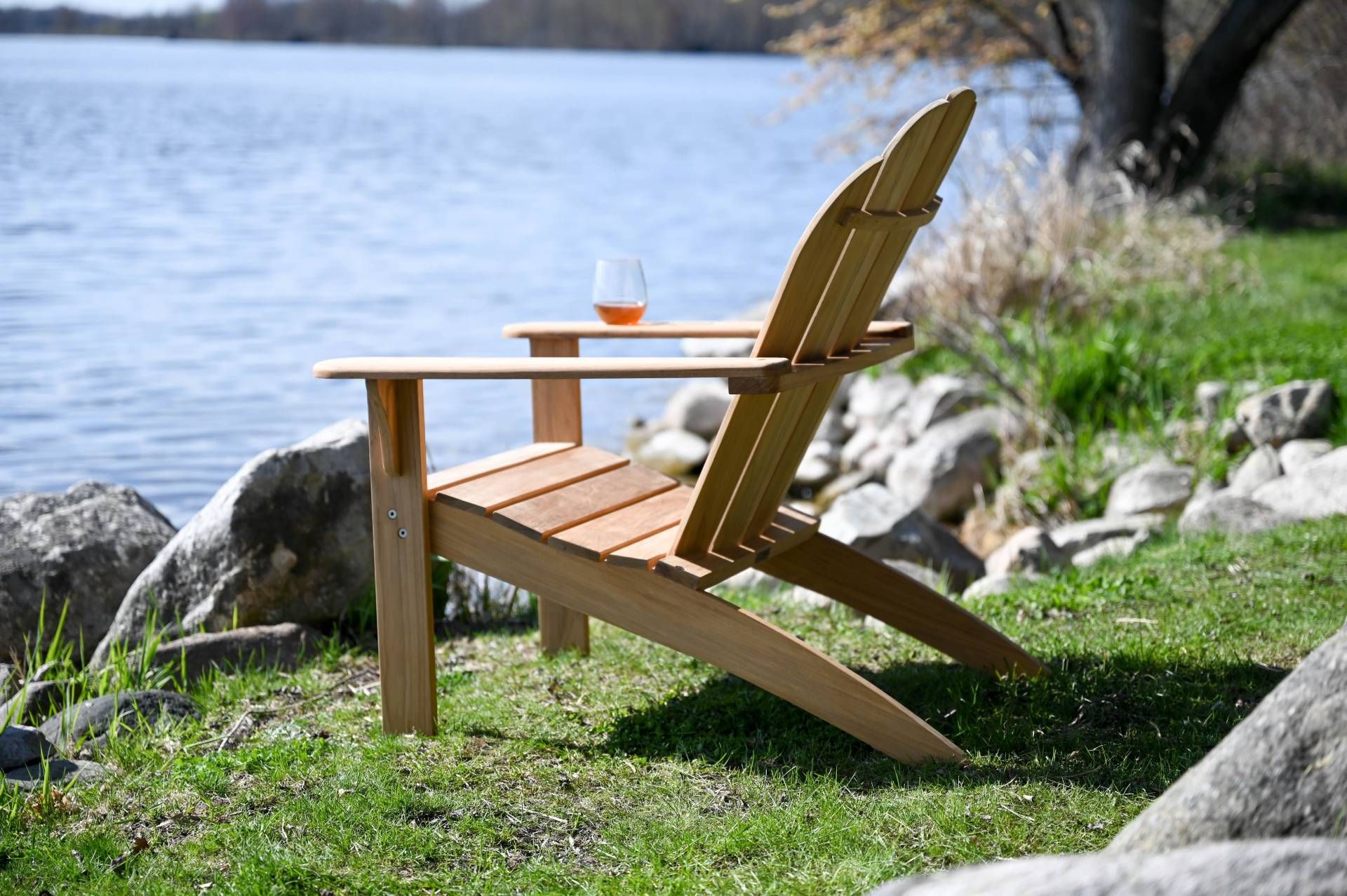 Wooden Adirondack chair with drink, lakeside.