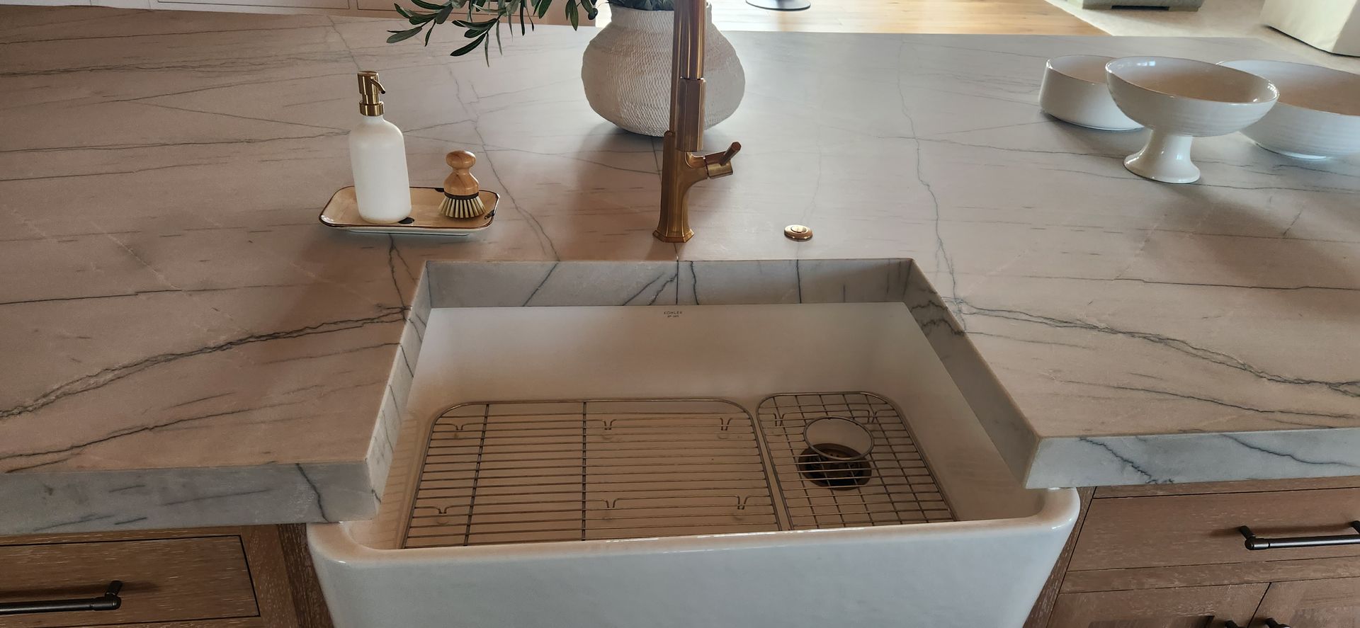 Kitchen island with white porcelain sink, granite countertop, and gold faucet.