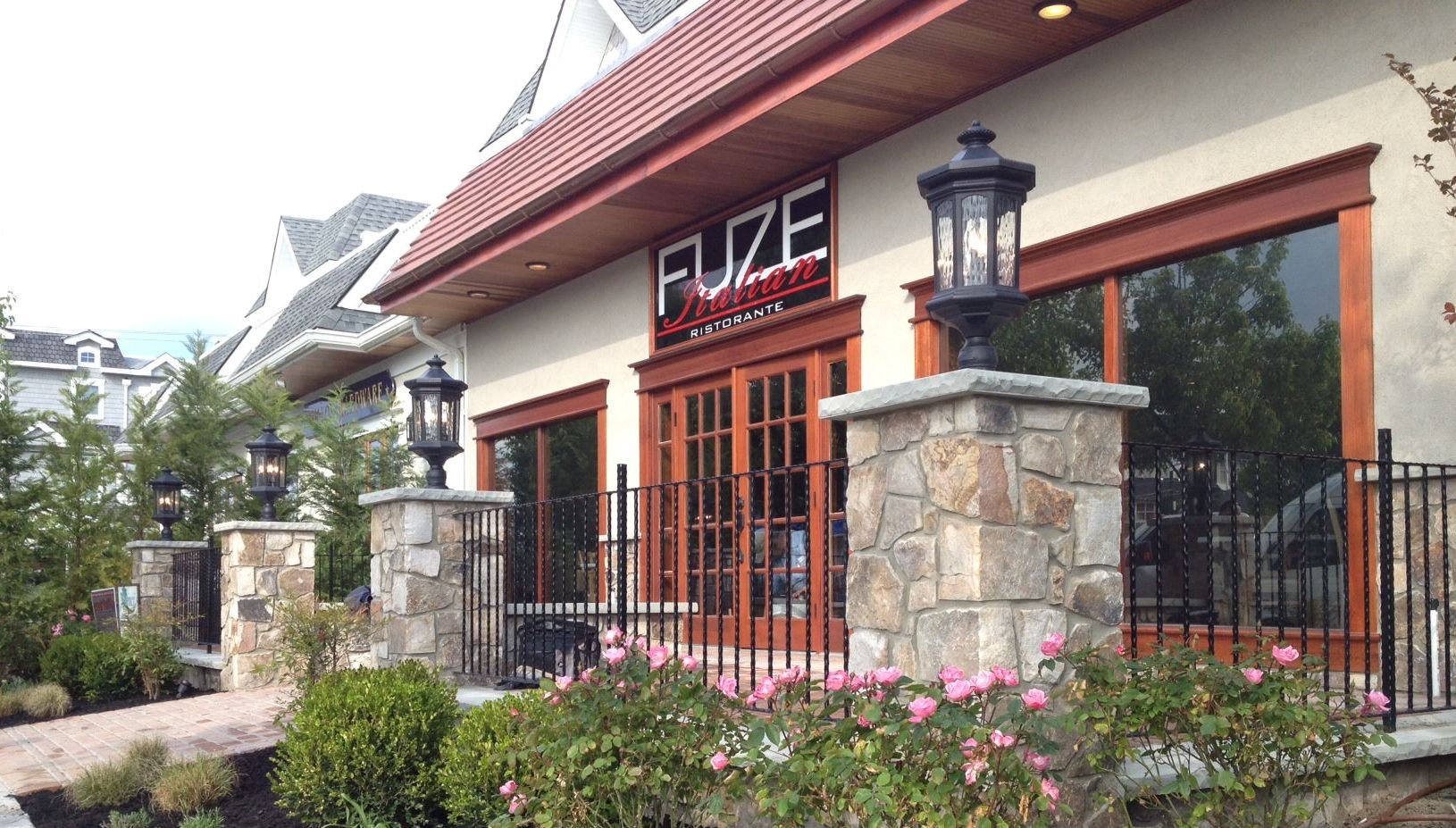Exterior of Fuze Restaurant with stone pillars, black lamps, and a red roof.