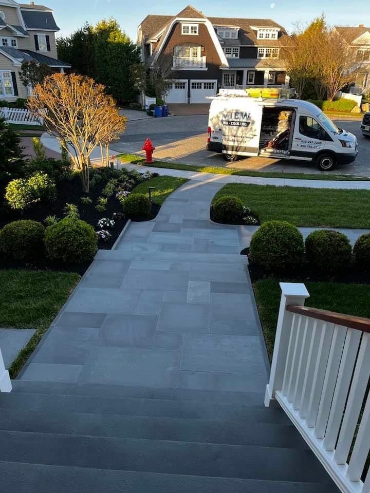 Stone steps leading to a walkway with landscaping. A van parked on the street in front of houses.