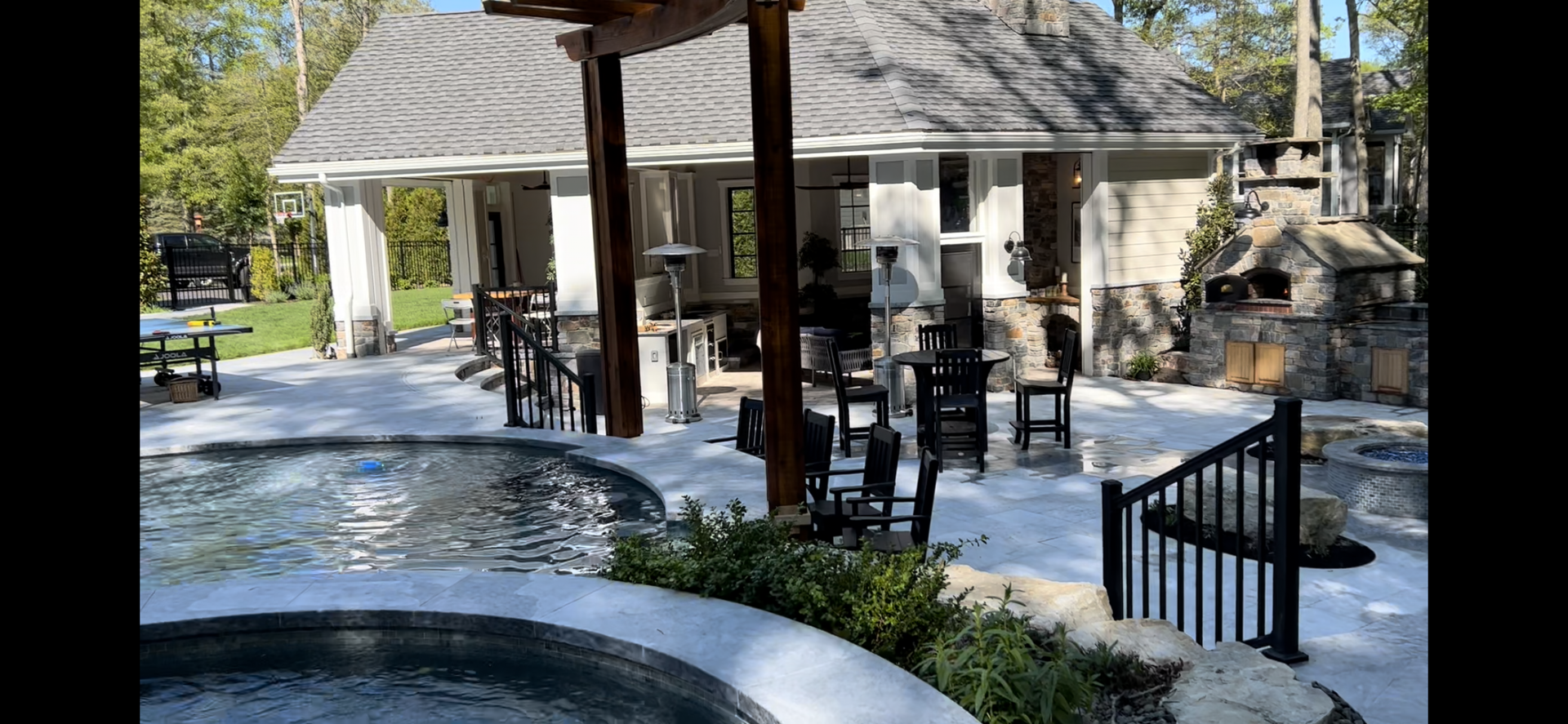 Outdoor patio with a pool, seating, bar, and stone oven.