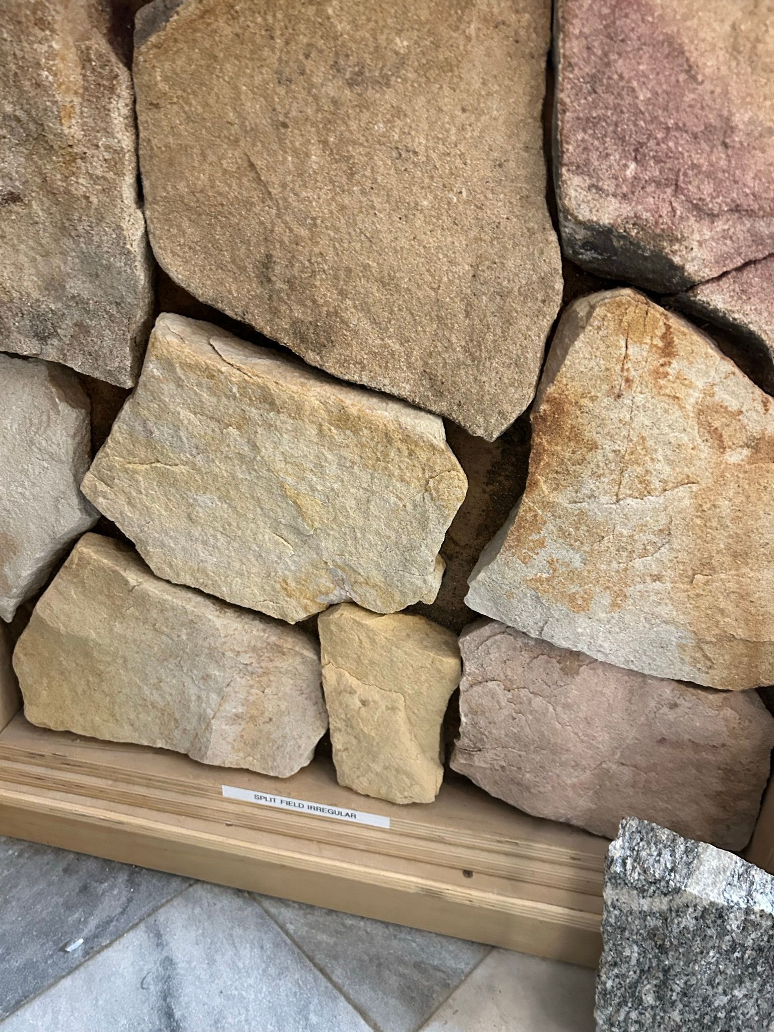 Close-up of irregularly-shaped, multi-colored stones, primarily tan, beige, and pink.