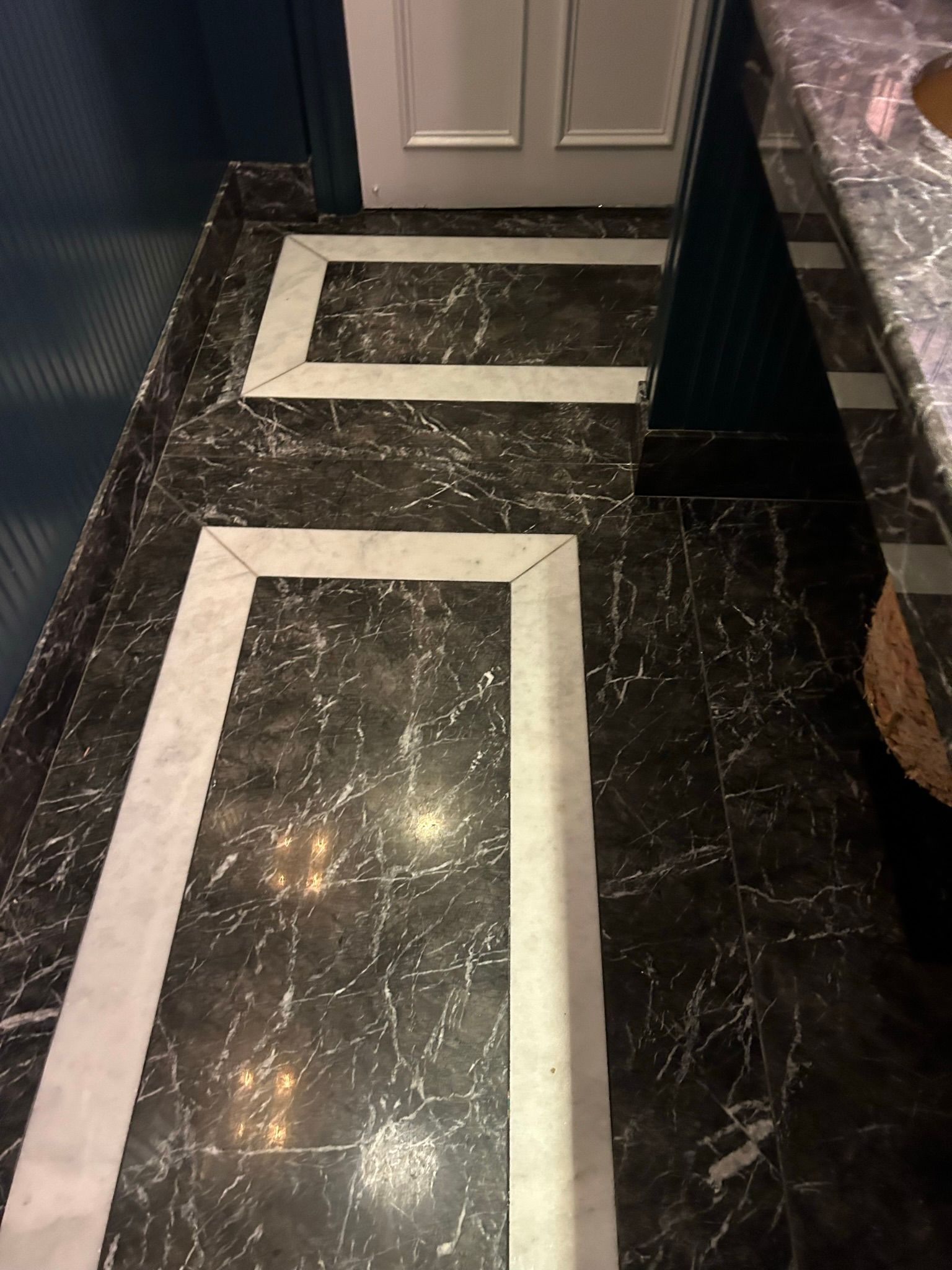 Dark marble bathroom floor with white border accents.