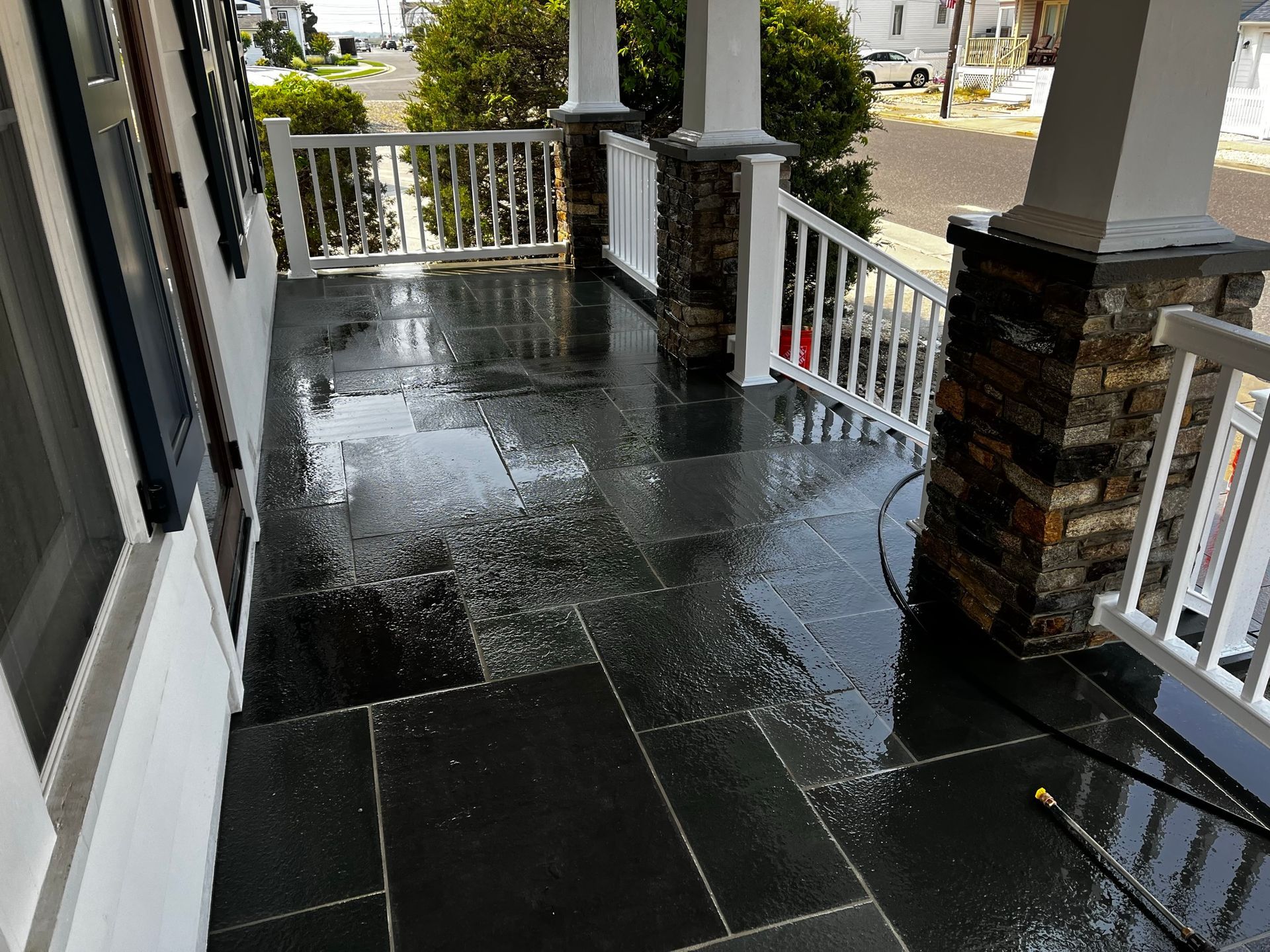 Wet, dark stone porch; white railing and columns.