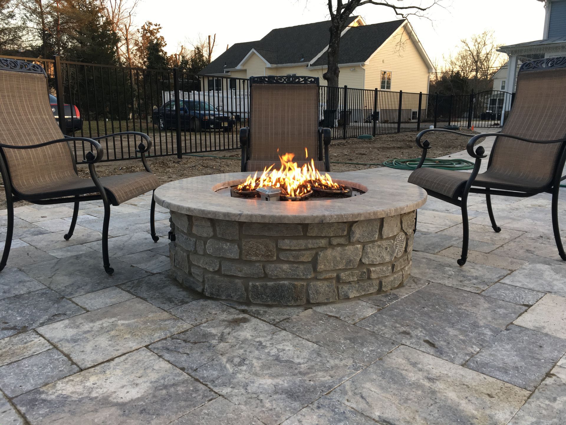 Fire pit with burning flames, surrounded by stone patio and seating.
