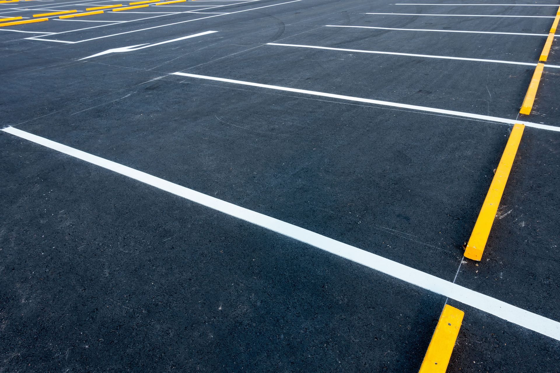 Empty asphalt parking lot with white and yellow painted lines.