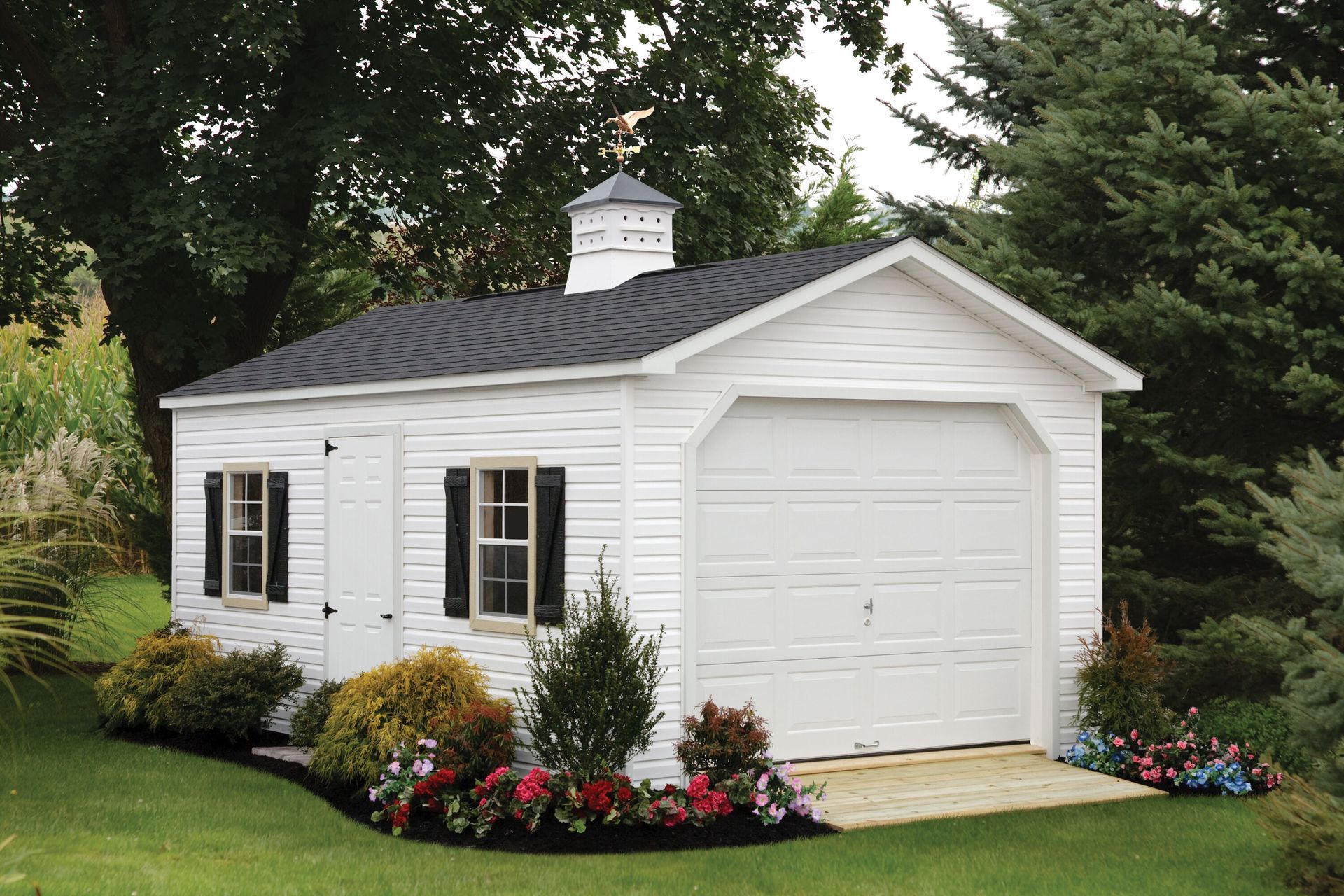 a white garage with a black roof and black shutters