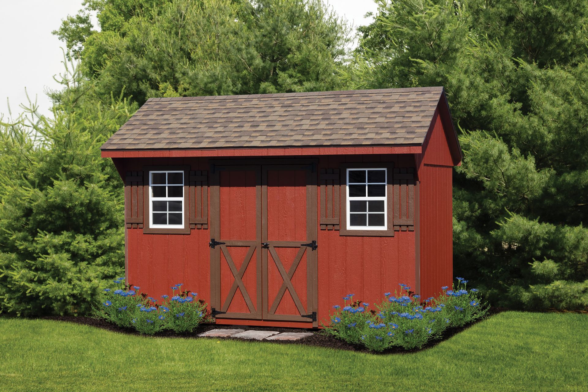 a red shed is sitting in the middle of a lush green field .