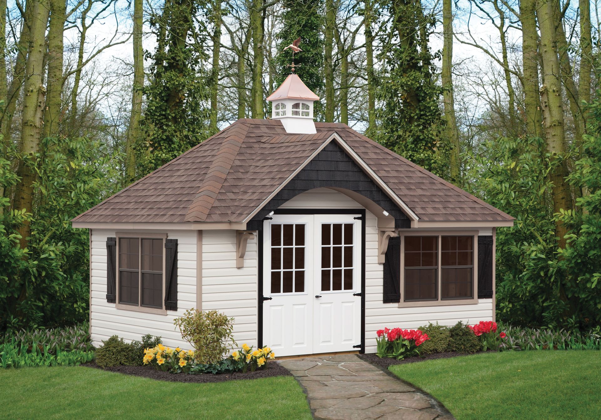 a small white house with a brown roof is surrounded by trees