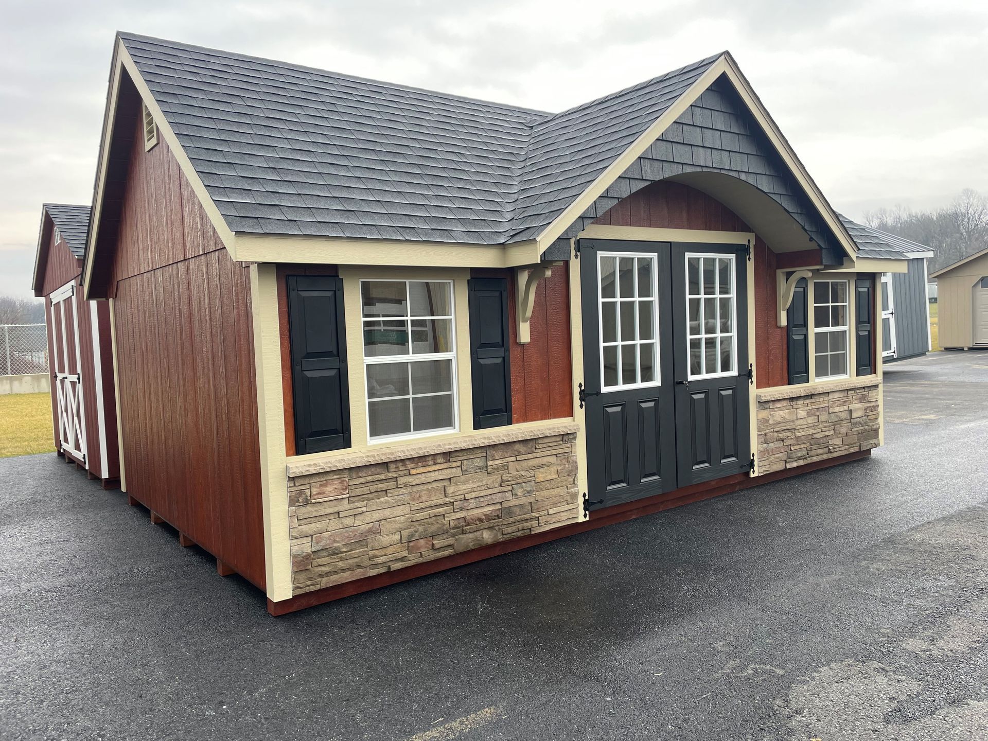 a small house with a roof and shutters is sitting on the side of the road .