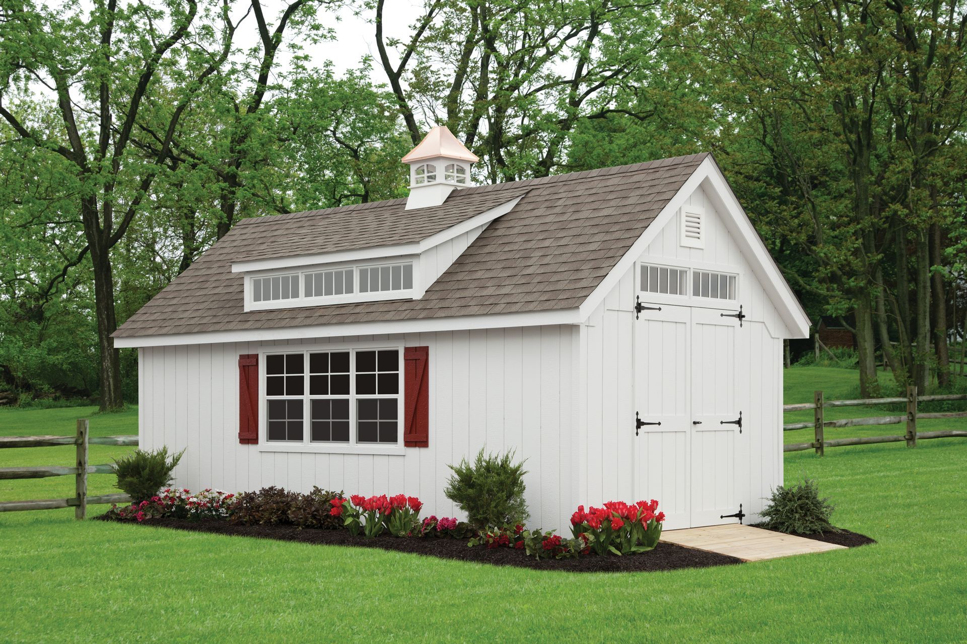 a white shed with a brown roof and red shutters