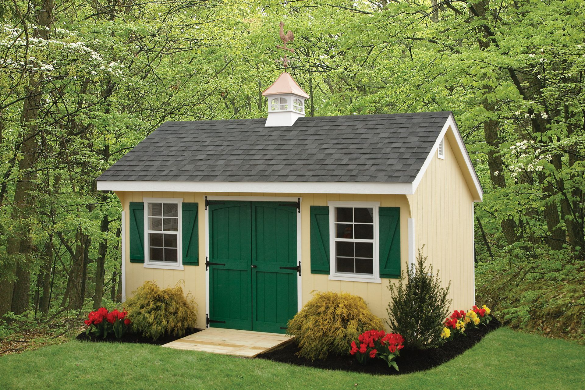 a yellow shed with green doors and shutters